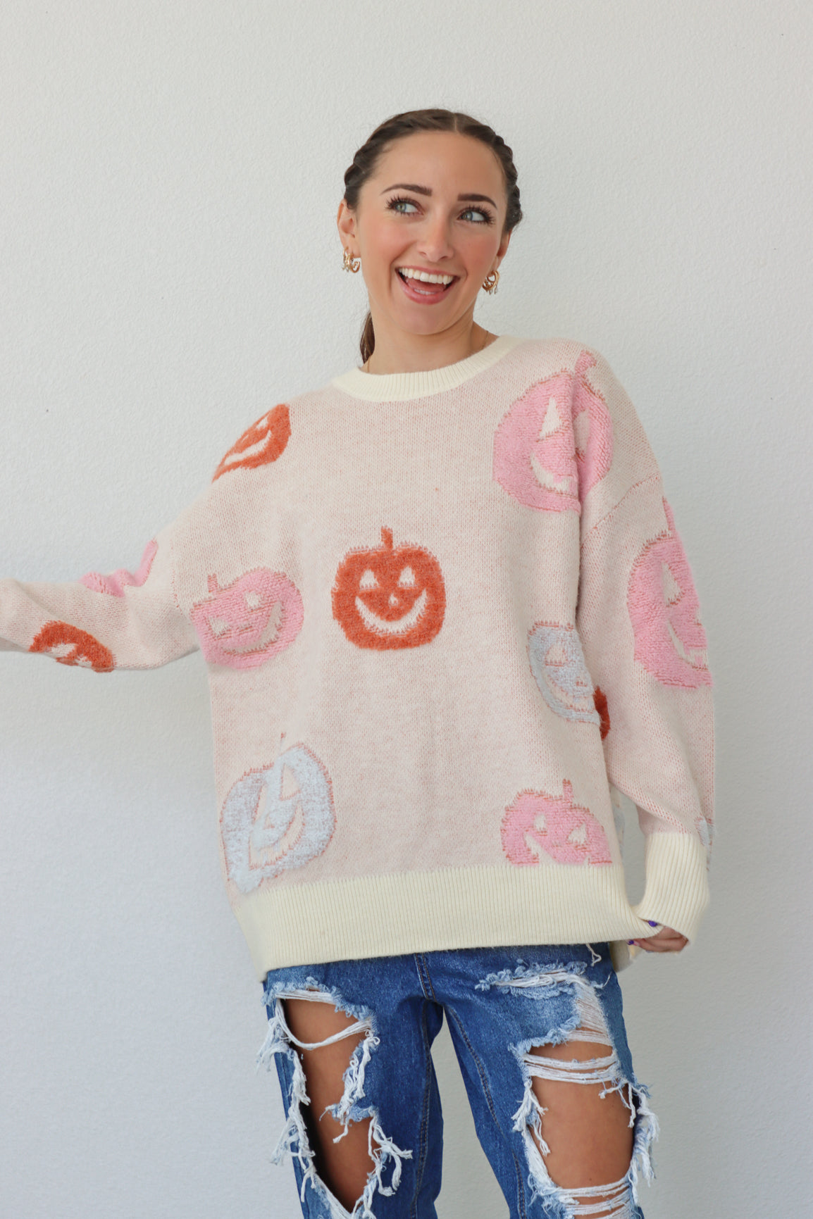 girl wearing cream sweater with pastel pumpkins