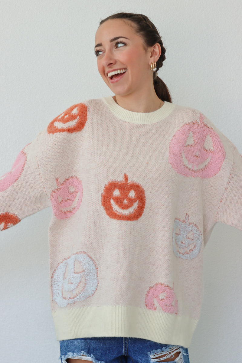 girl wearing cream sweater with pastel pumpkins