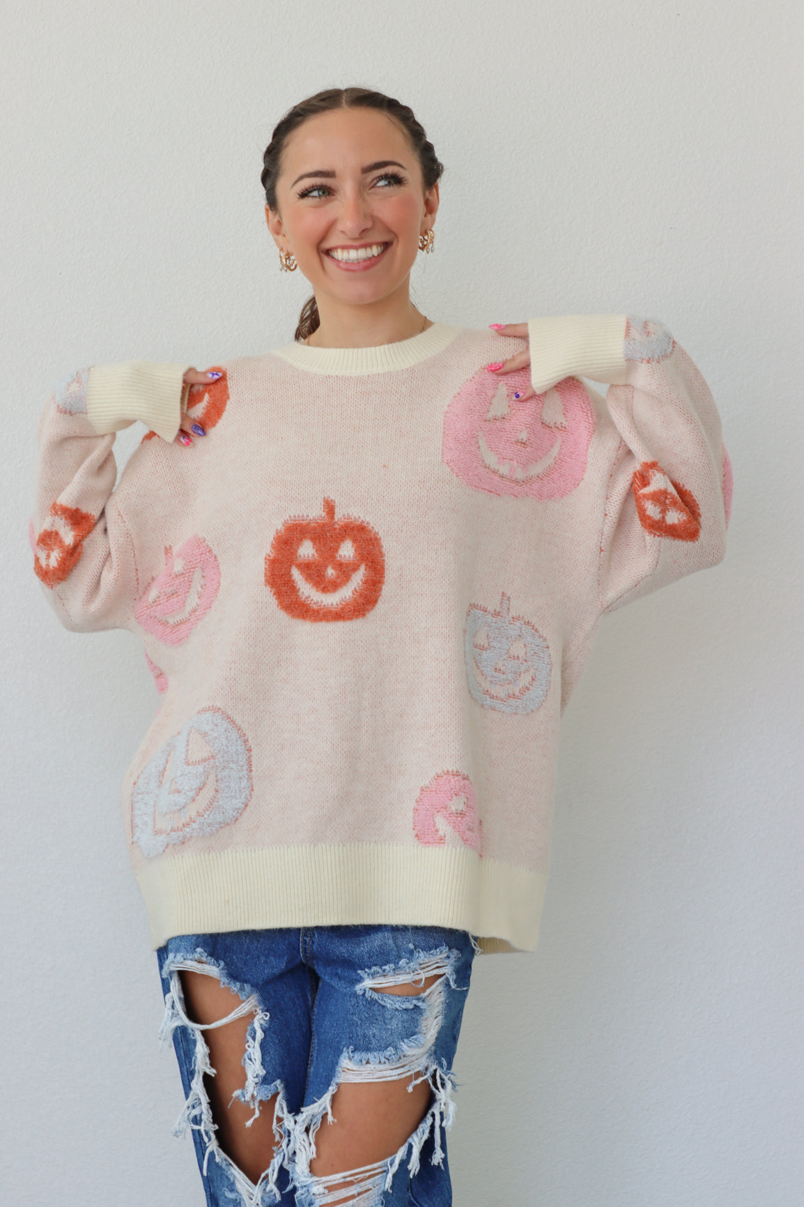 girl wearing cream sweater with pastel pumpkins