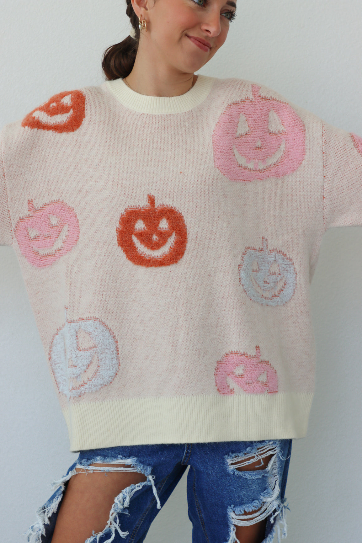 girl wearing cream sweater with pastel pumpkins