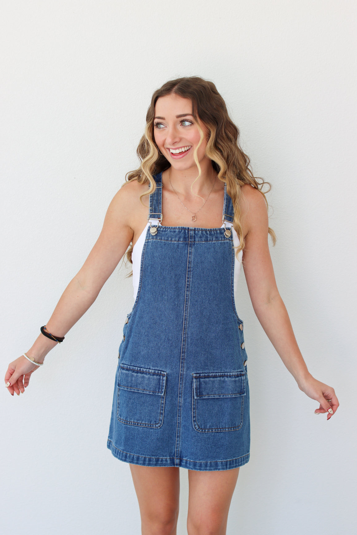 Woman wearing a denim overall dress against a white background