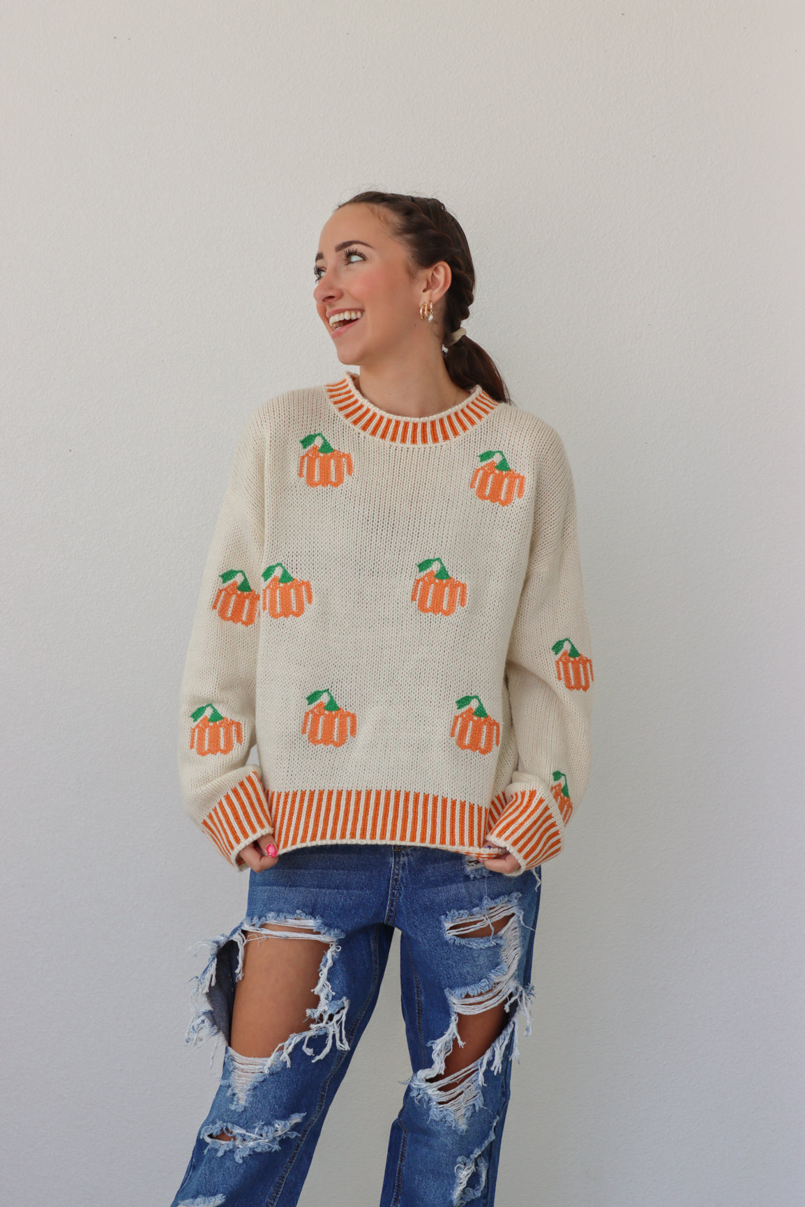 girl wearing cream sweater with orange pumpkin design