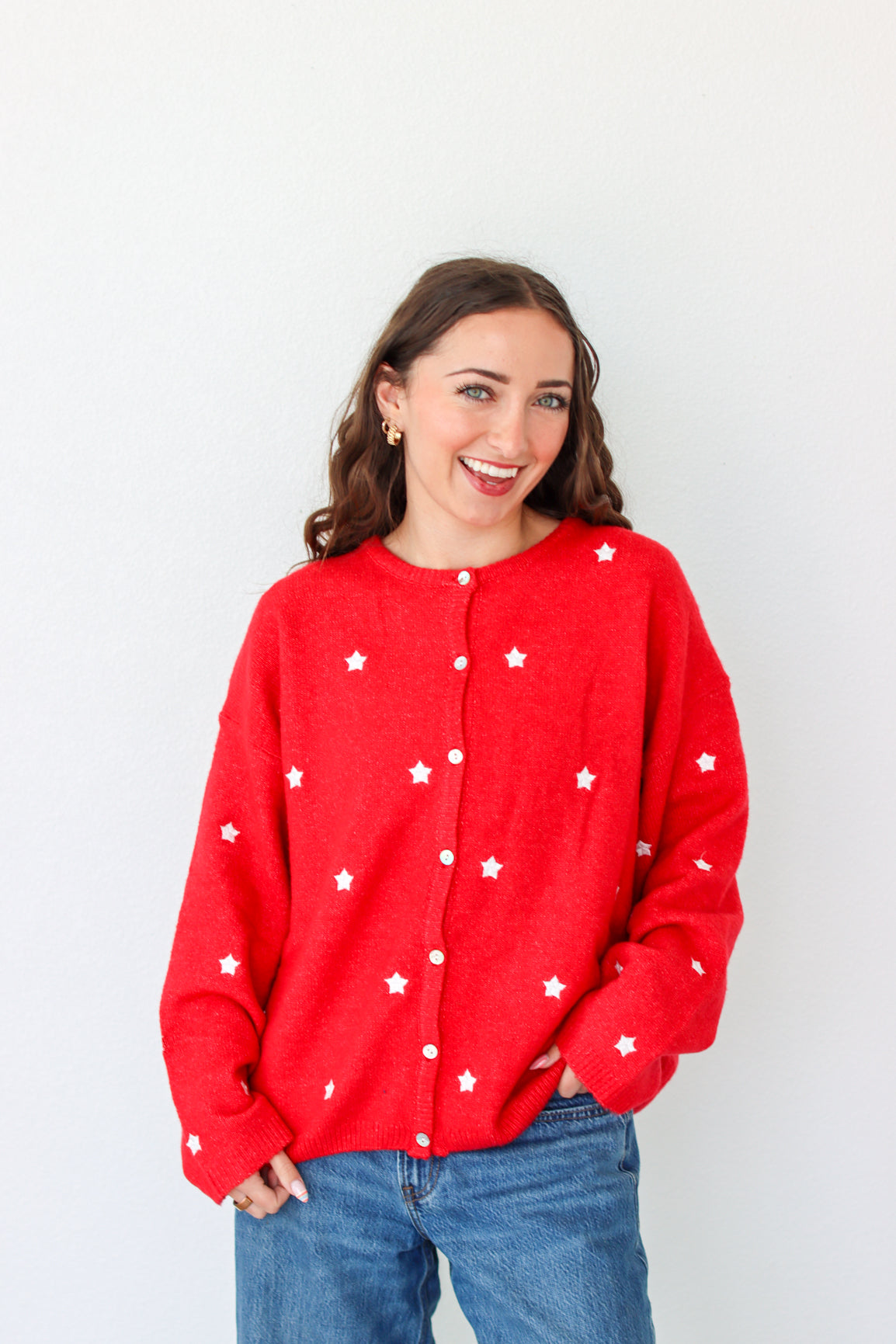 Woman wearing a red cardigan with white star patterns against a plain background