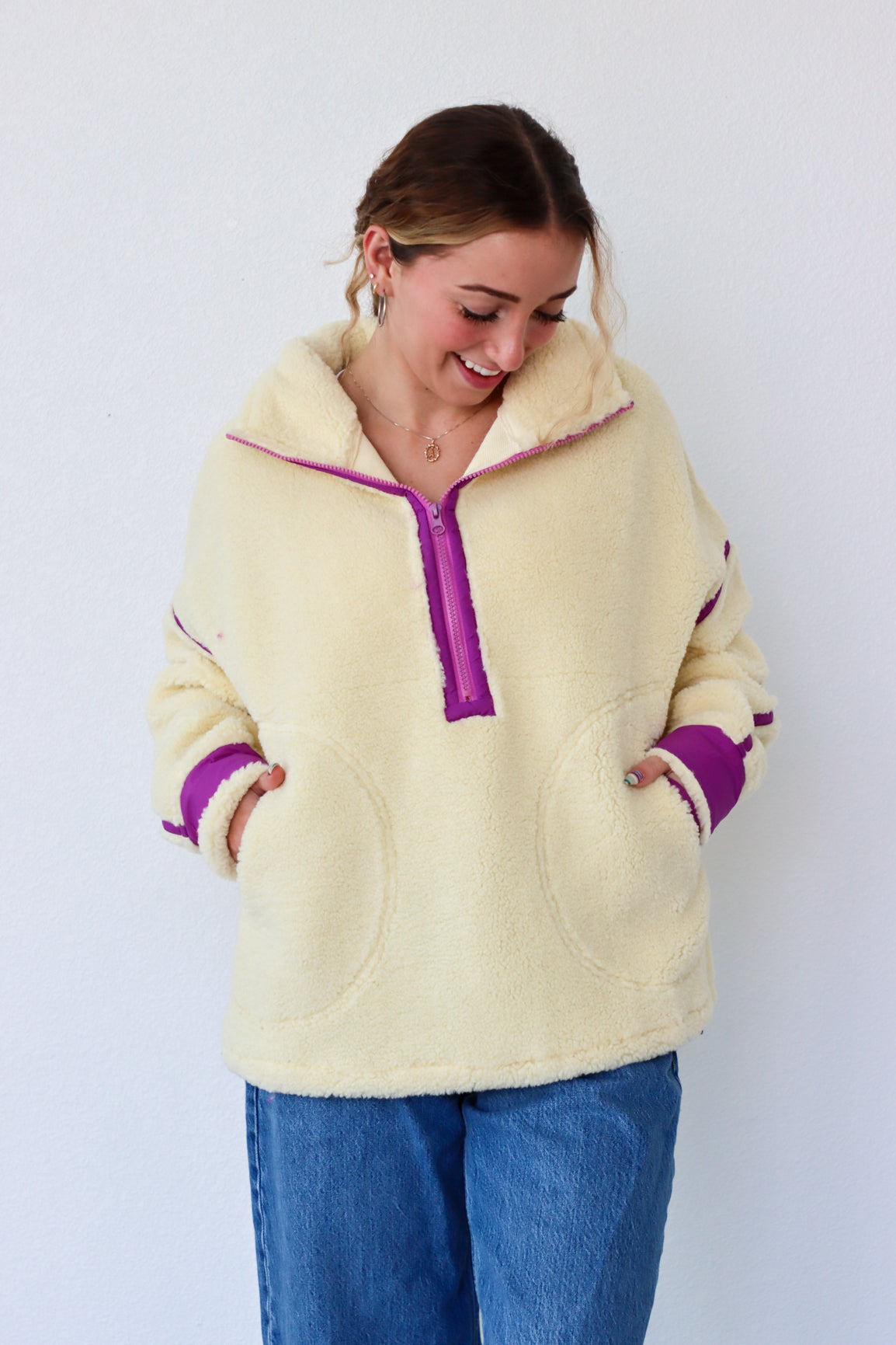 Woman wearing a cream fleece pullover with purple accents against a white background