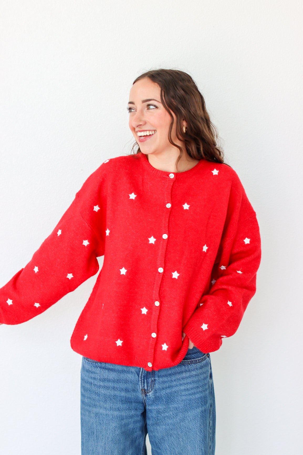 Woman wearing a red cardigan with white star patterns against a plain background