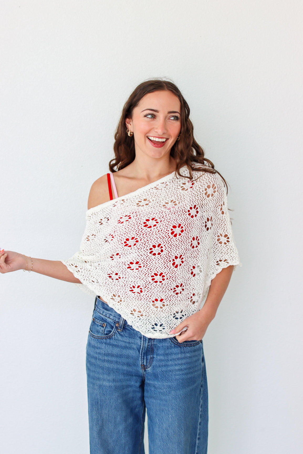 Woman wearing a white crochet shawl with patterns against a plain background