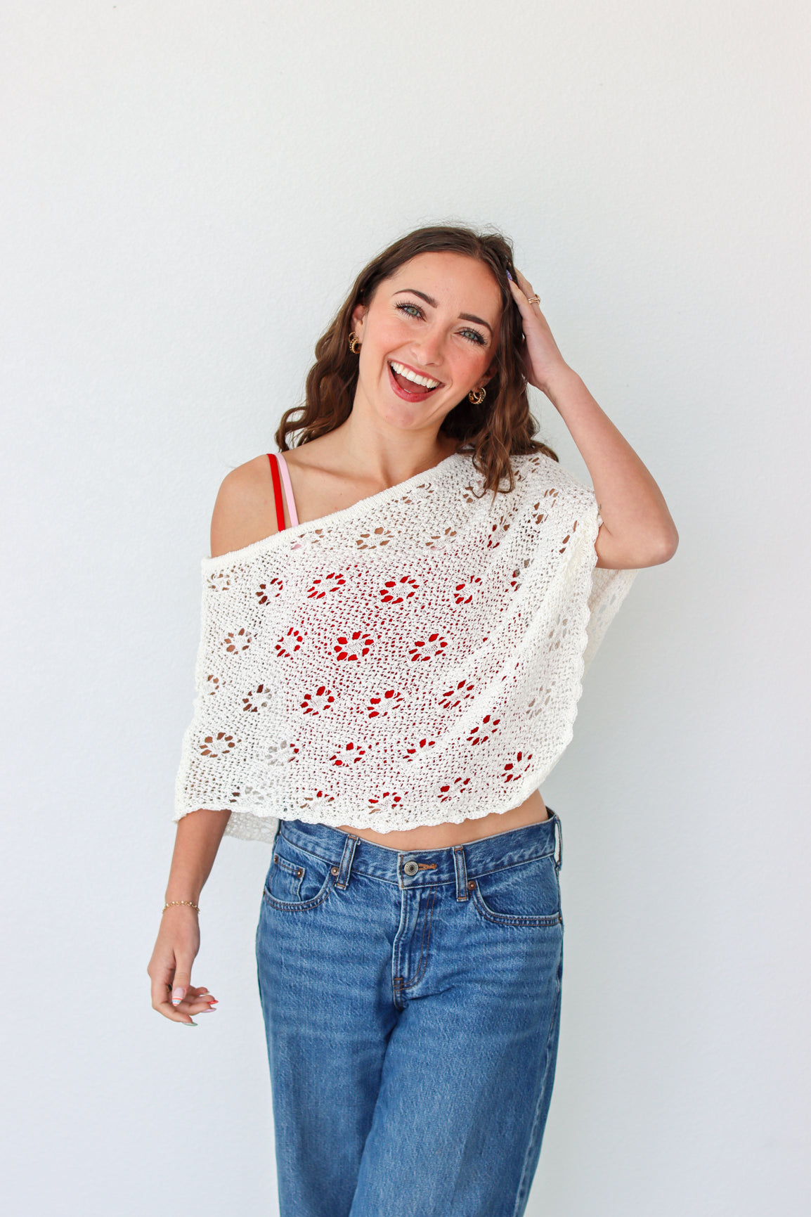 Woman wearing a white crochet shawl with patterns against a plain background