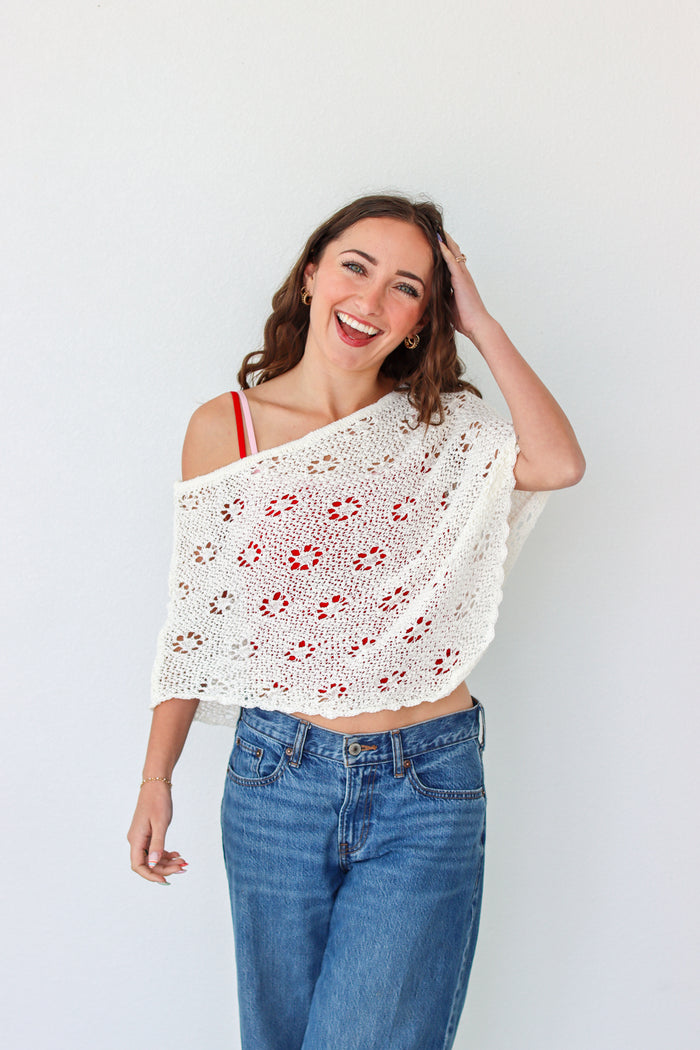 Woman wearing a white crochet shawl with patterns against a plain background