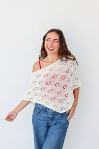 Woman wearing a white crochet shawl with patterns against a plain background
