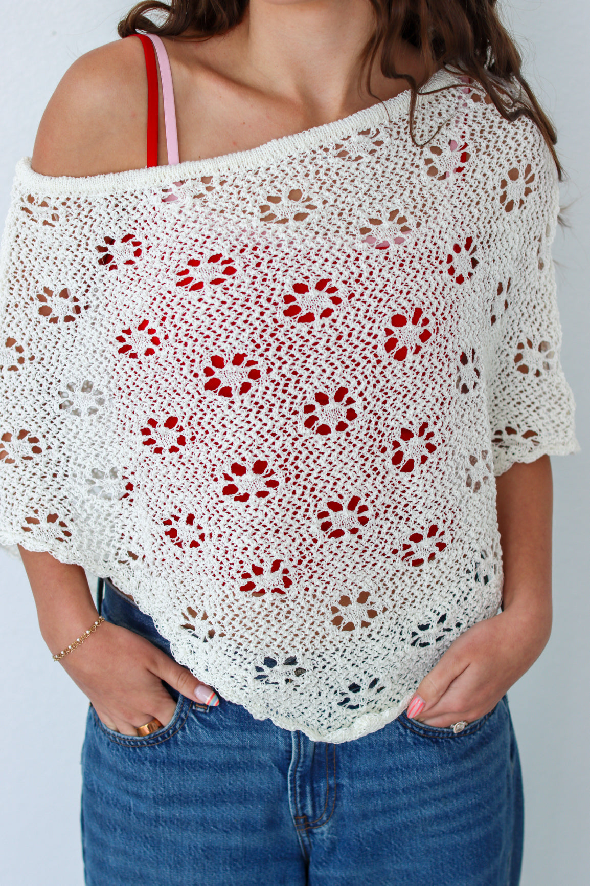 Woman wearing a white crochet shawl with patterns against a plain background
