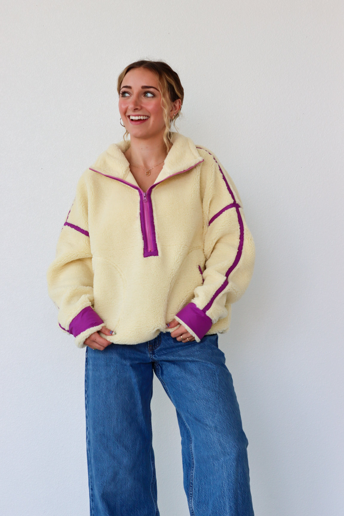 Woman wearing a yellow fleece pullover with purple accents against a white background