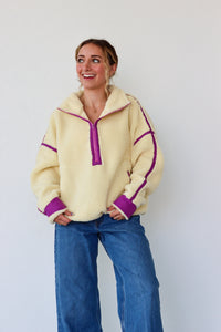 Woman wearing a yellow fleece pullover with purple accents against a white background
