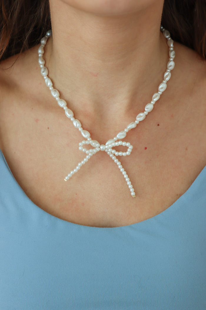 girl wearing pearl bow necklace