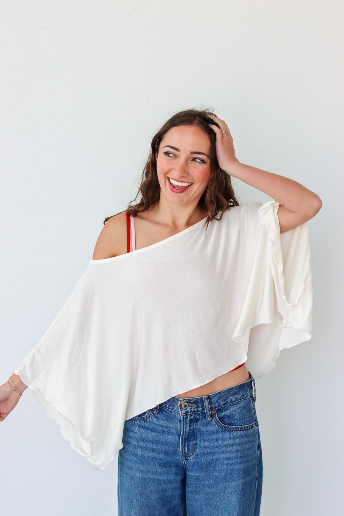 Woman wearing a white top and blue jeans against a white background