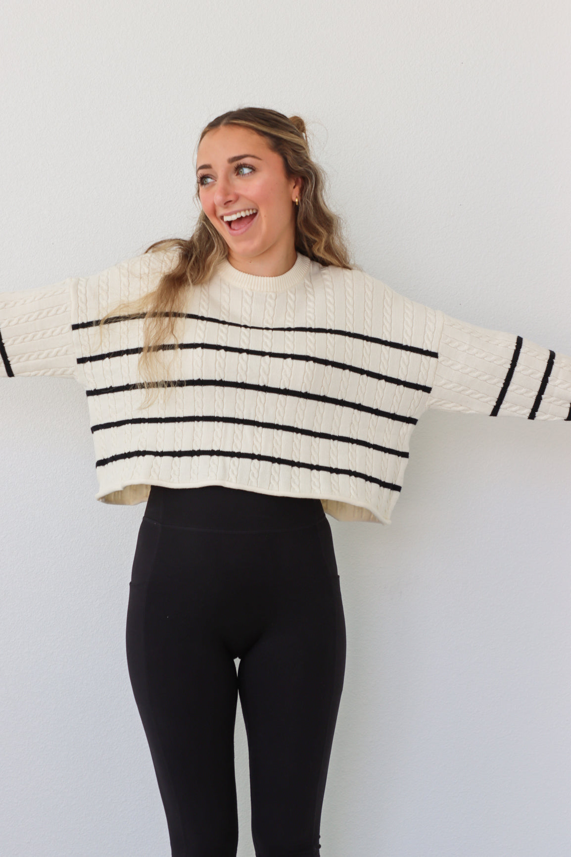 girl wearing cream cable knit sweater with black stripes