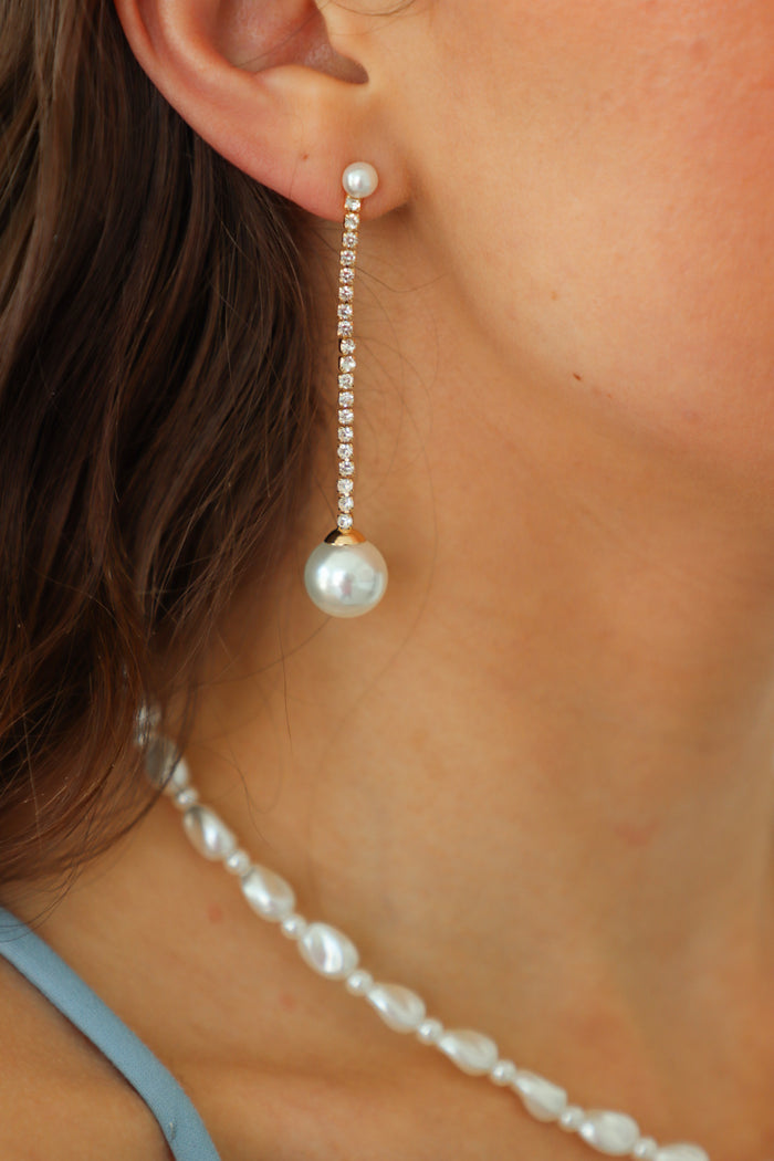 girl wearing gold rhinestone earring with pearl detailing