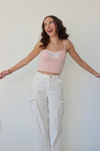 girl wearing cropped pink tank top with butterfly applique