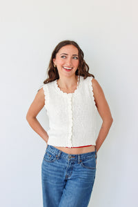 Woman wearing a white sleeveless top and blue jeans against a white background