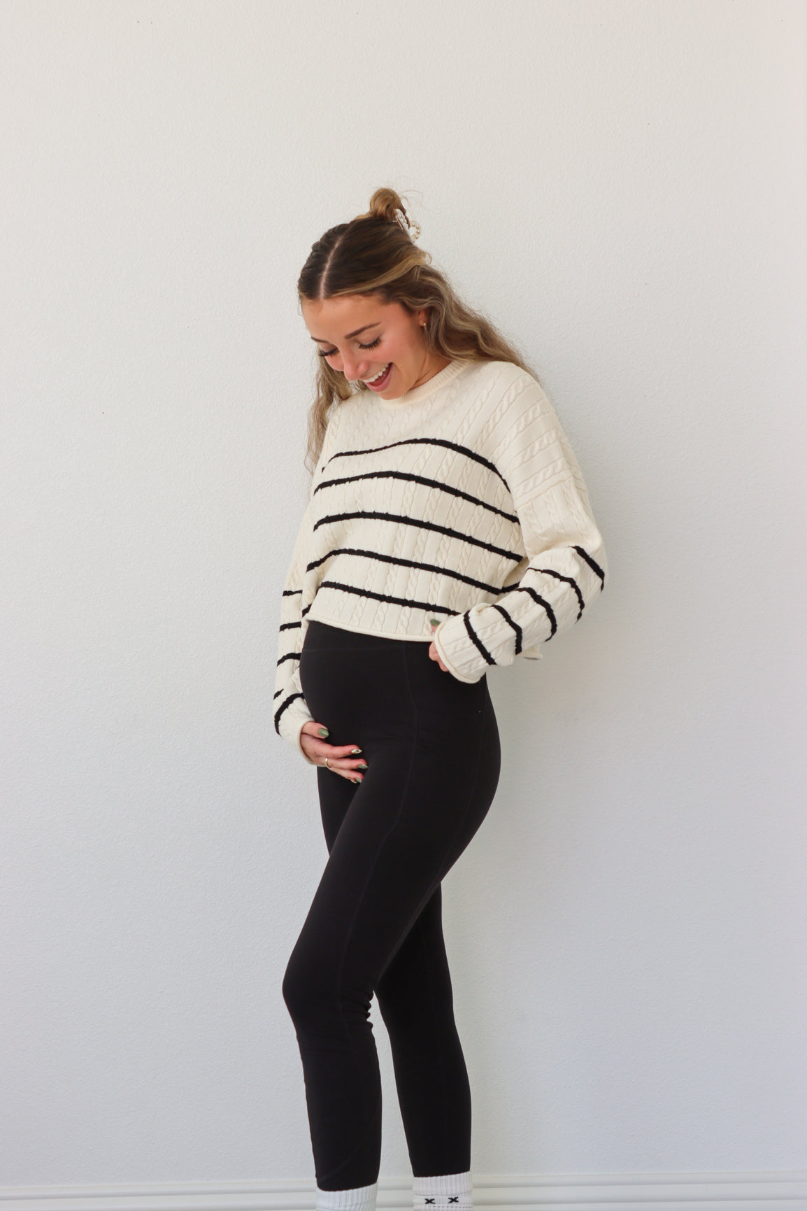 girl wearing cream cable knit sweater with black stripes