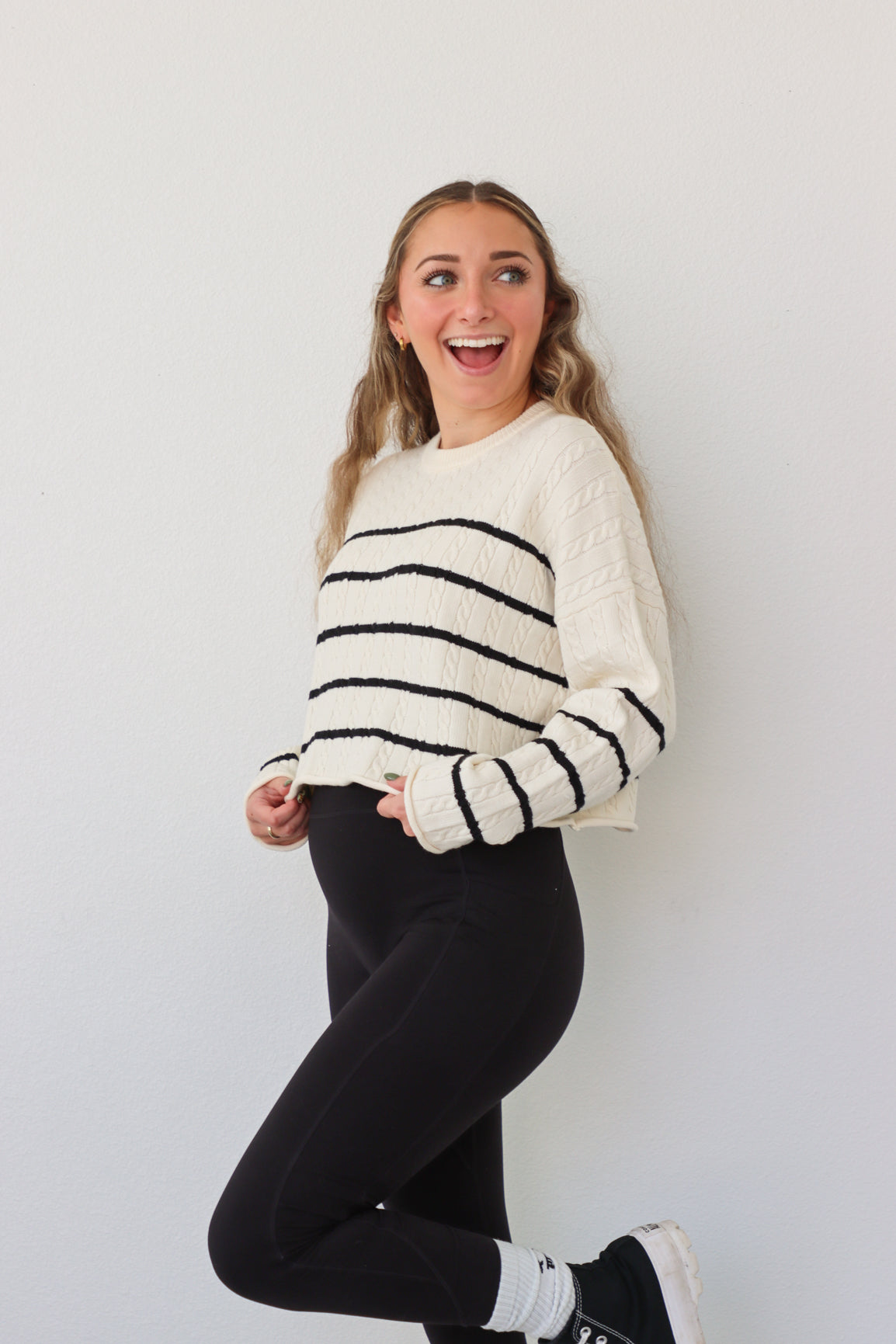 girl wearing cream cable knit sweater with black stripes