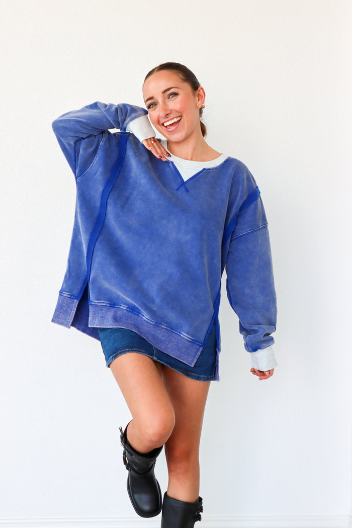 Woman wearing a blue oversized sweatshirt and black boots on a white background