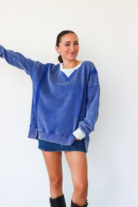 Woman wearing a blue oversized sweatshirt and denim shorts on a white background