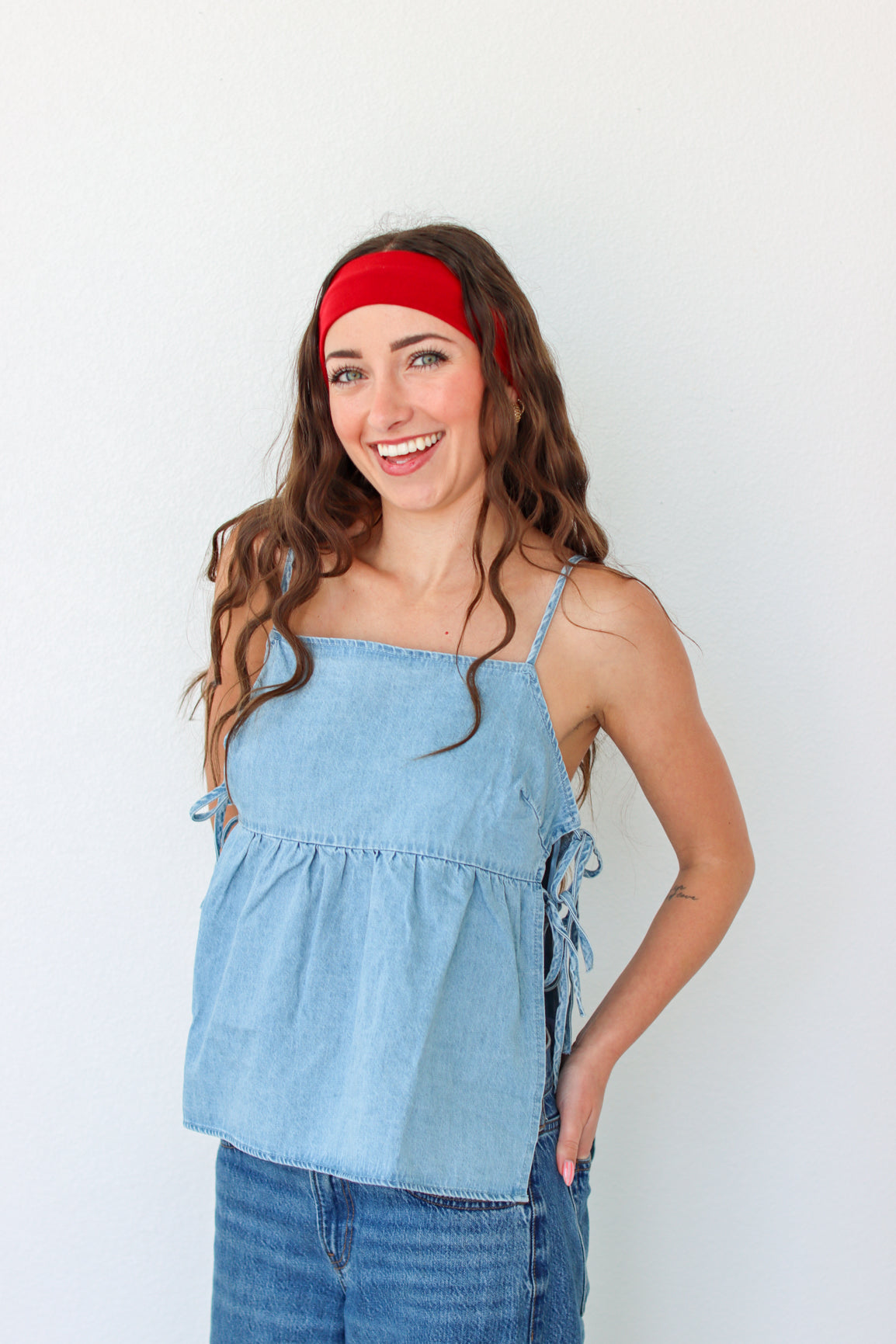 Woman wearing a denim top and red headband against a white background