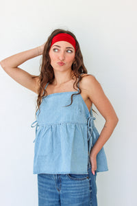Woman wearing a light blue denim top and jeans with a red headband against a white background