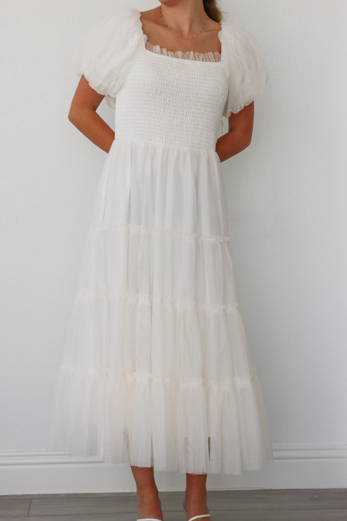girl wearing long white dress with tulle detailing