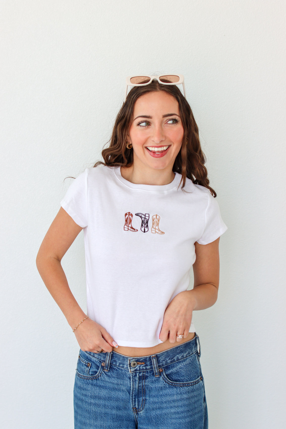 Woman wearing a white t-shirt with a graphic design and blue jeans against a white background