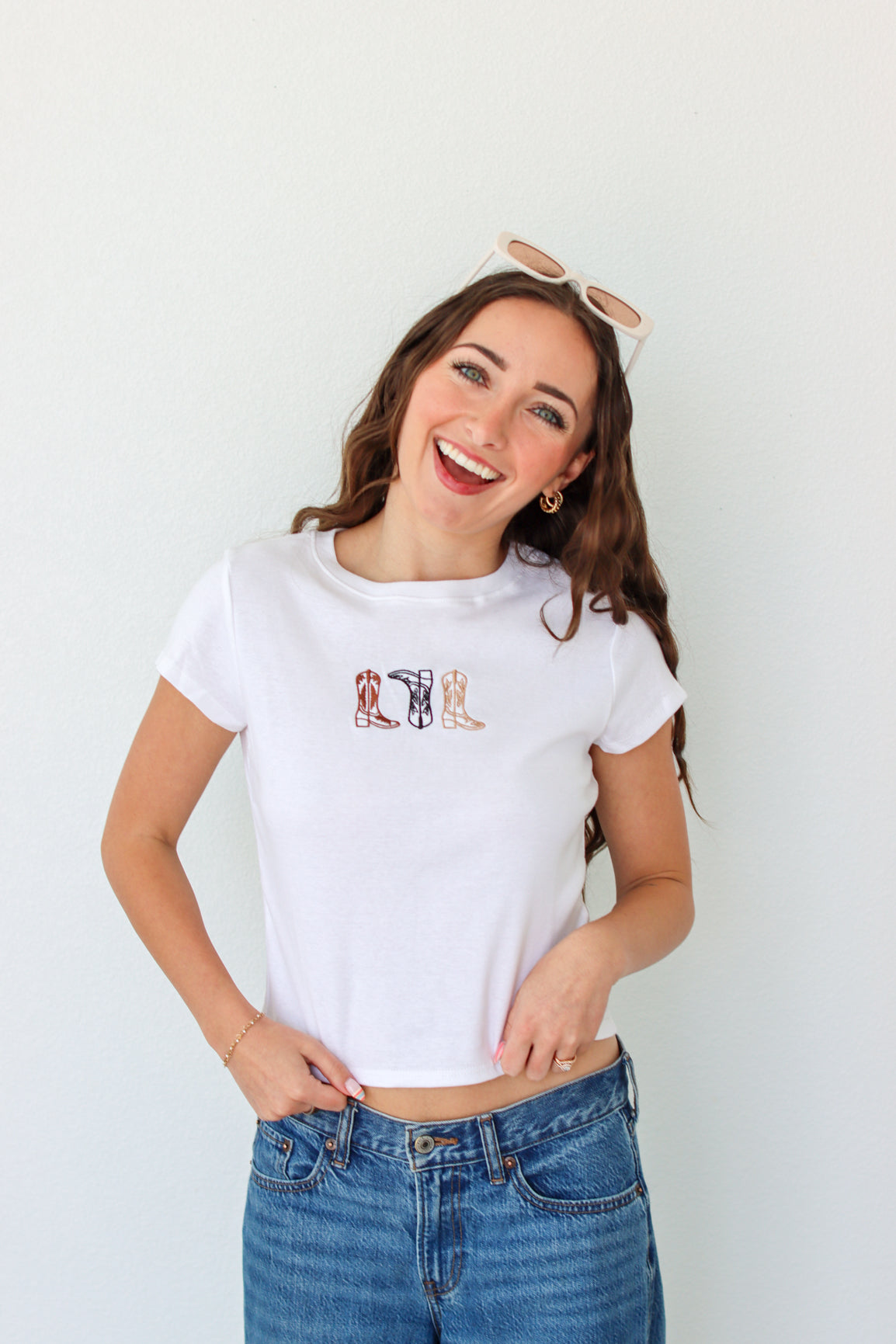 Woman wearing a white t-shirt with a graphic design and blue jeans against a white background