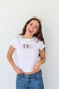 Woman wearing a white t-shirt with a graphic design and blue jeans against a white background