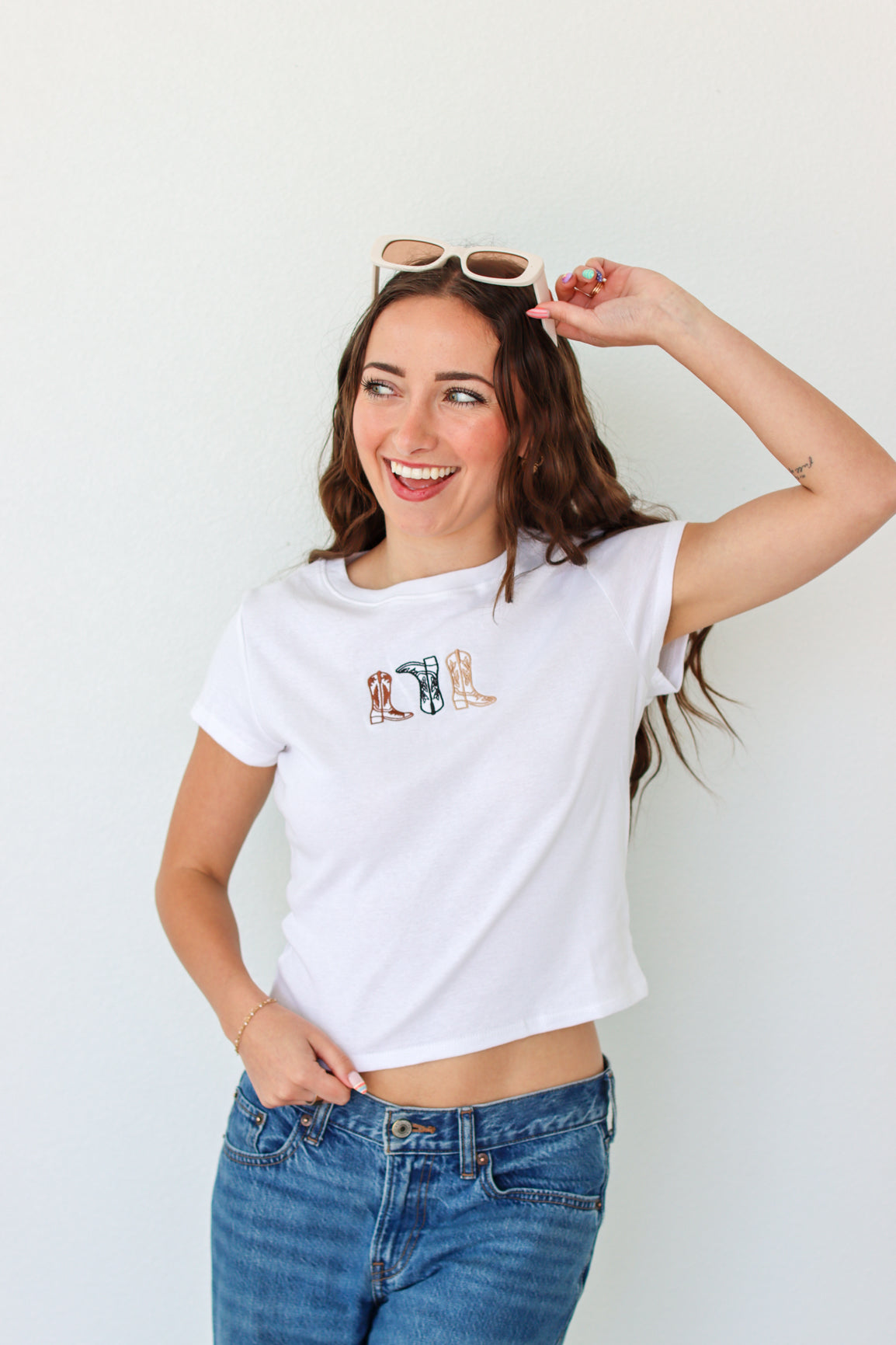 Woman wearing a white t-shirt with a graphic design and blue jeans against a white background
