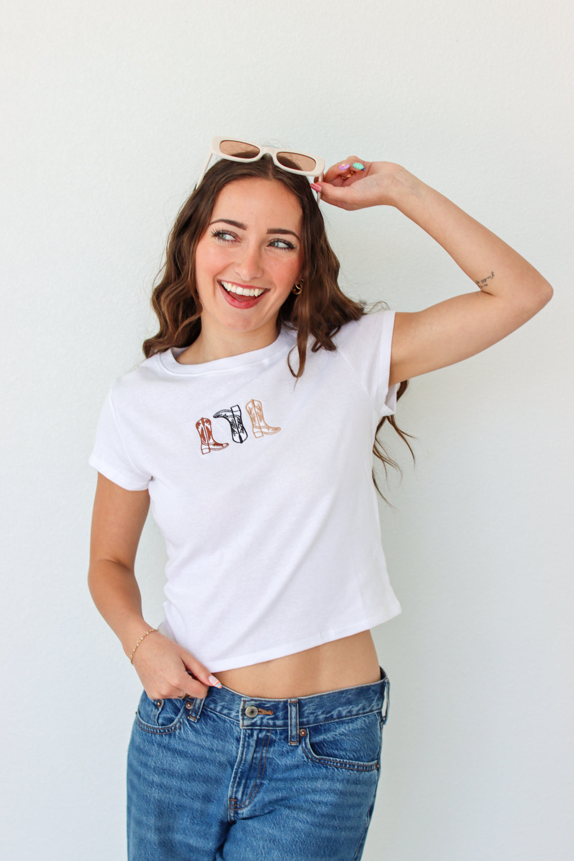 Woman wearing a white t-shirt with a graphic design and blue jeans against a white background