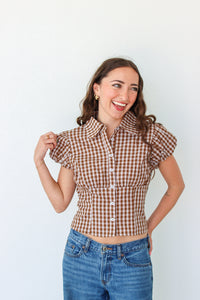 Woman wearing a brown checkered shirt and jeans against a white background