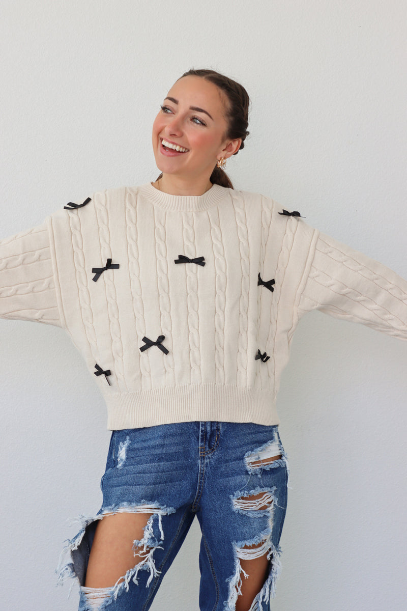 girl wearing cream sweater with black bows