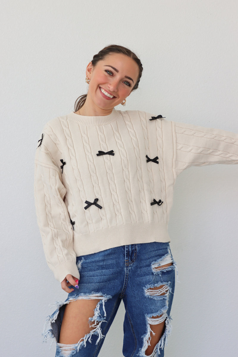 girl wearing cream sweater with black bows