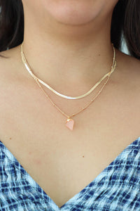 girl wearing gold chain necklace with pink stone charm