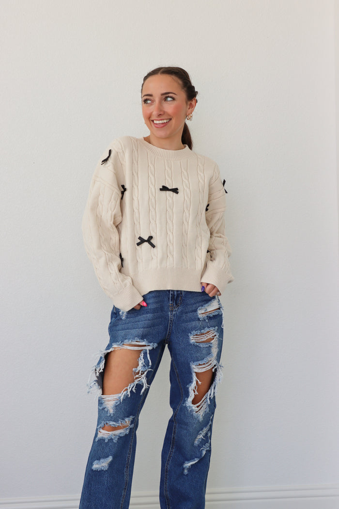 girl wearing cream sweater with black bows