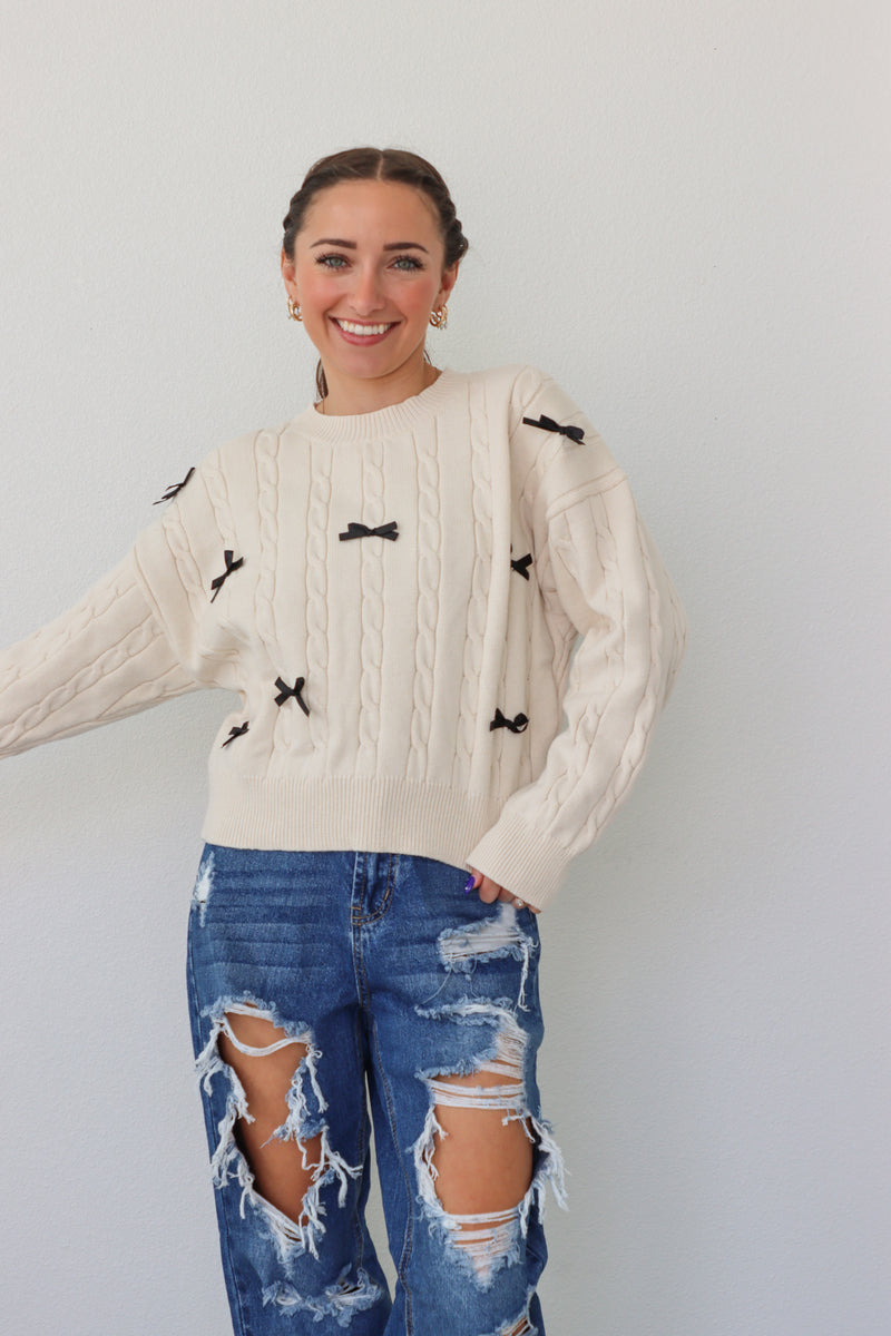 girl wearing cream sweater with black bows