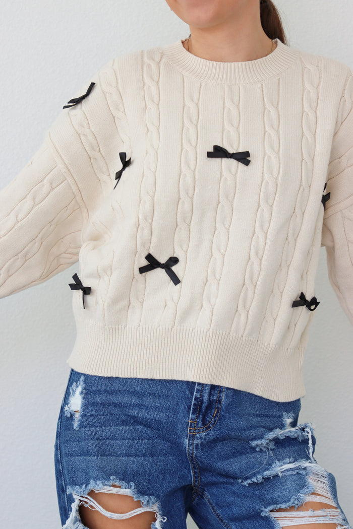 girl wearing cream sweater with black bows