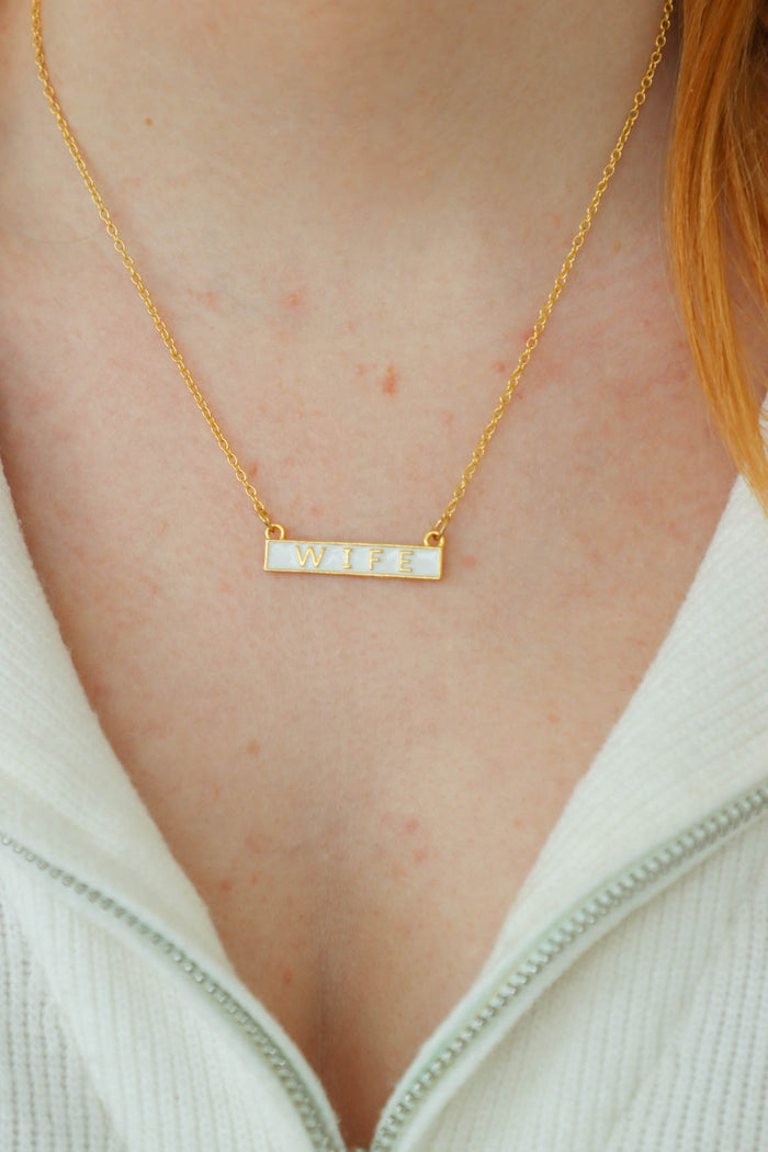 gold necklace with white "wife" bar pendant