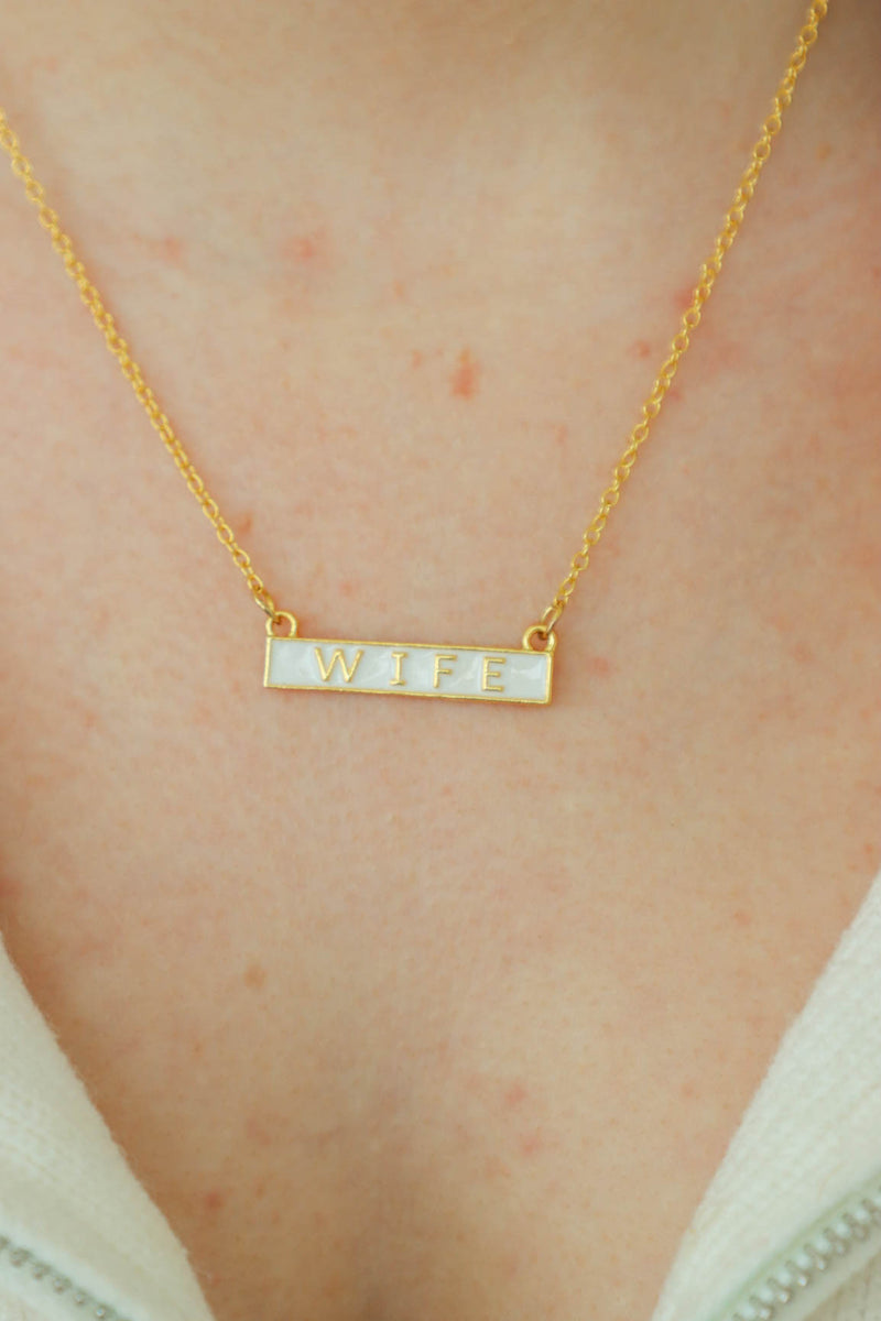 gold necklace with white "wife" bar pendant