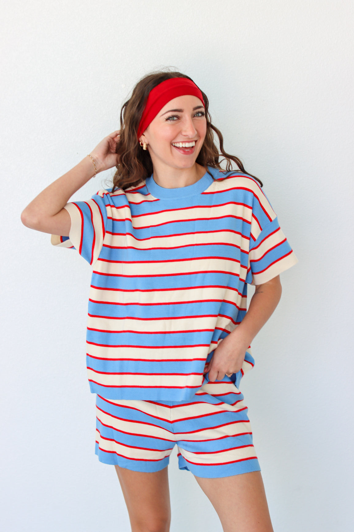 Woman wearing a blue and red striped outfit with a headband against a white background