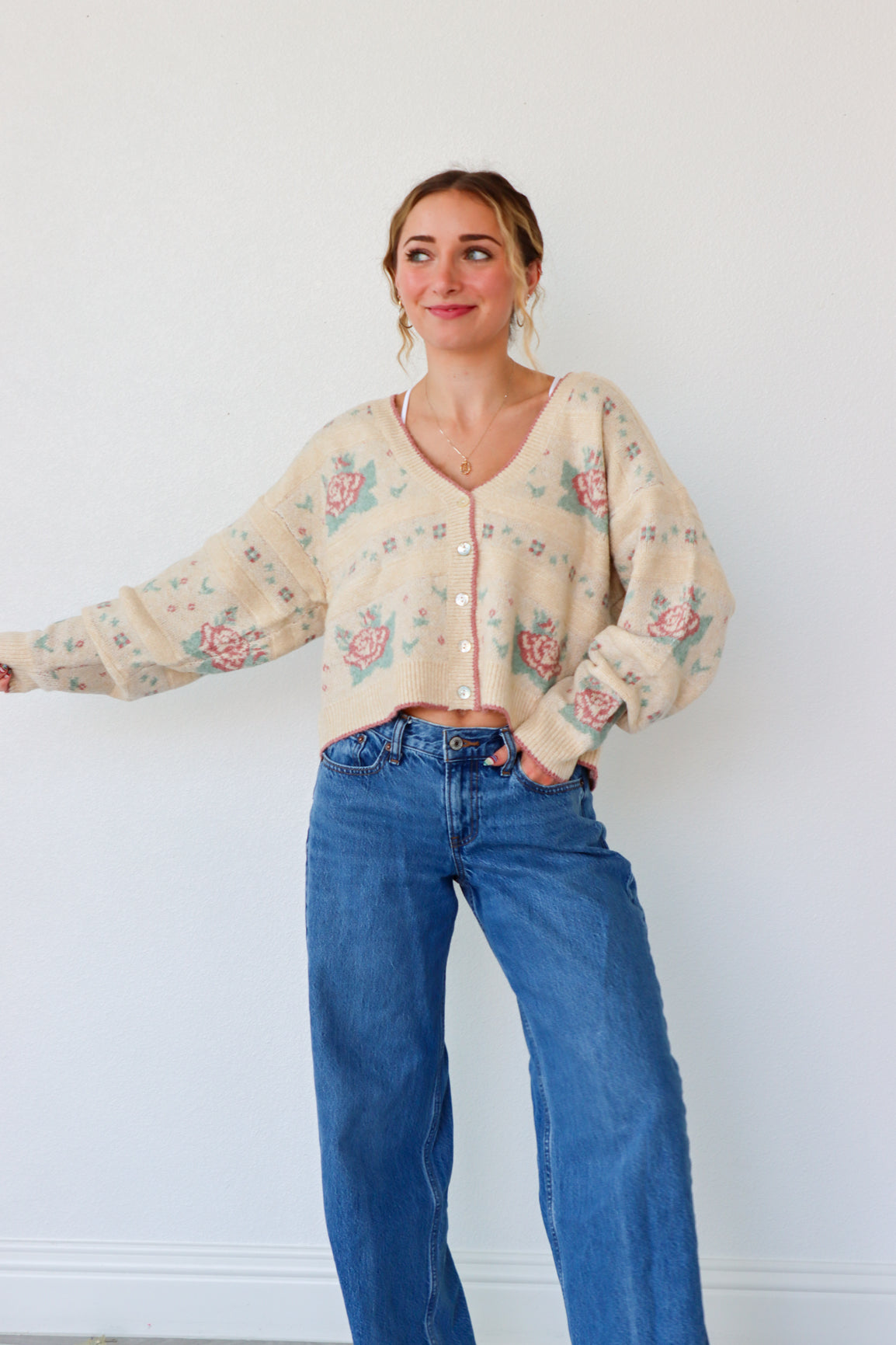 Woman wearing a floral blouse and blue jeans against a white background