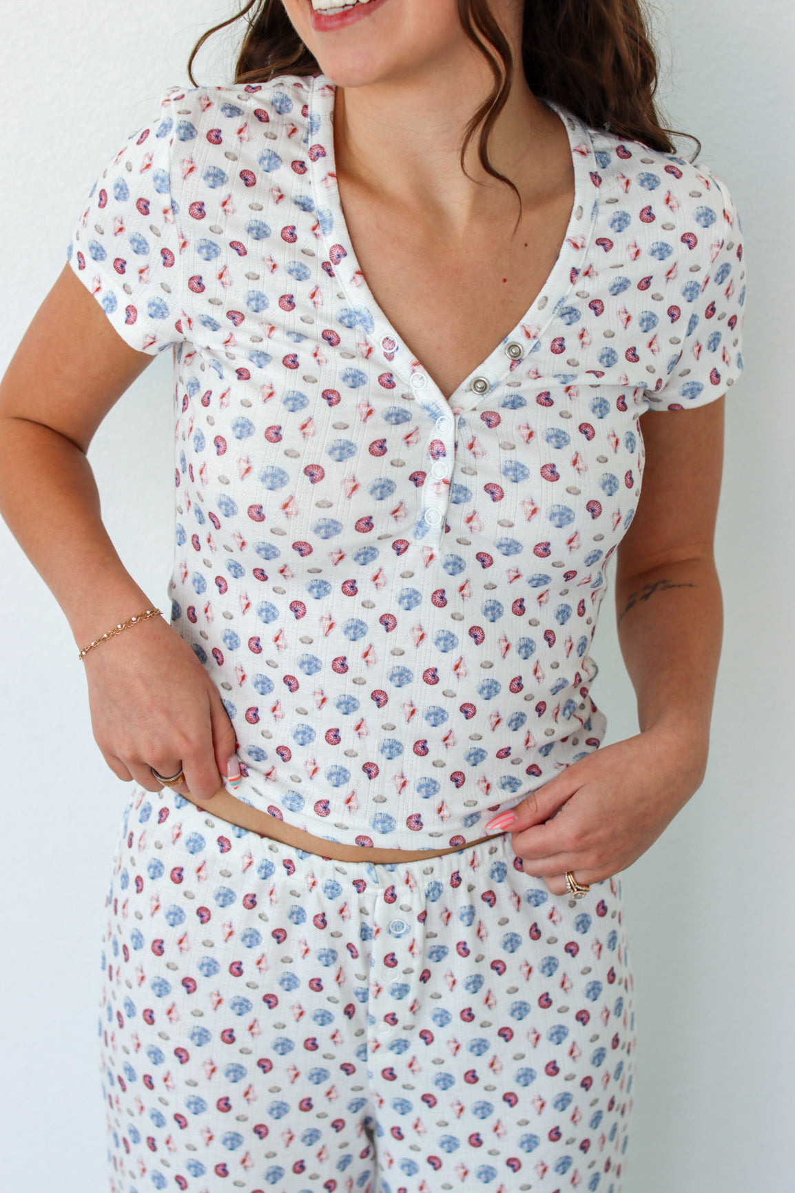 Close up of woman wearing a short sleeve top and pant PJ set with seashell prints 