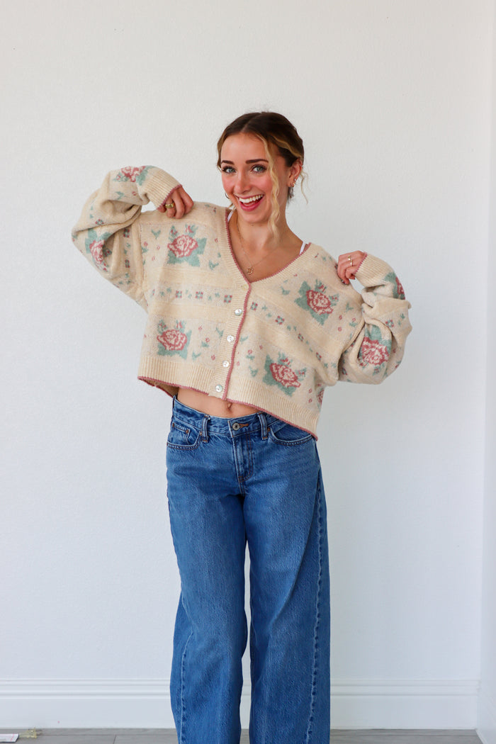 Woman wearing a floral cardigan and blue jeans against a white background
