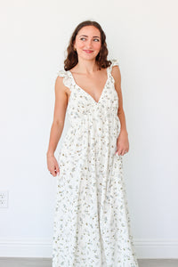 Woman wearing a white floral dress against a plain background