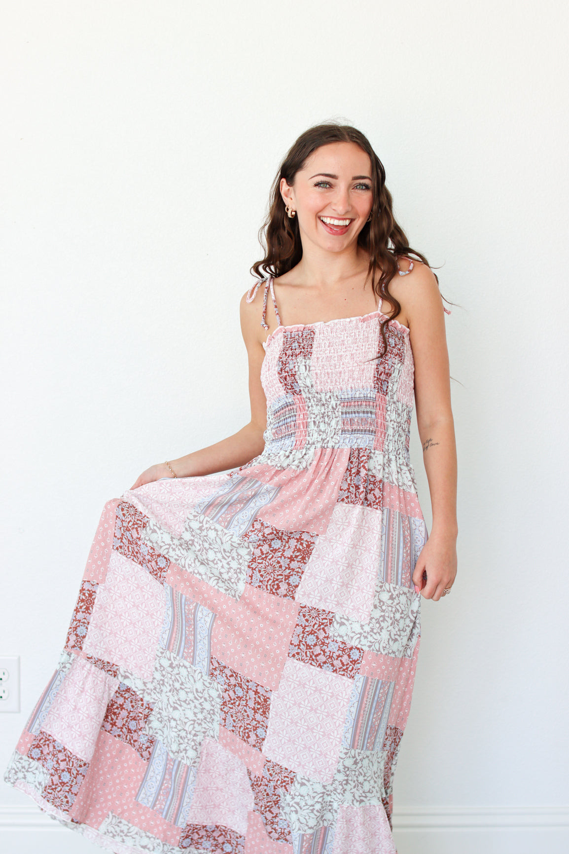 Woman wearing a pink floral patchwork dress against a white background