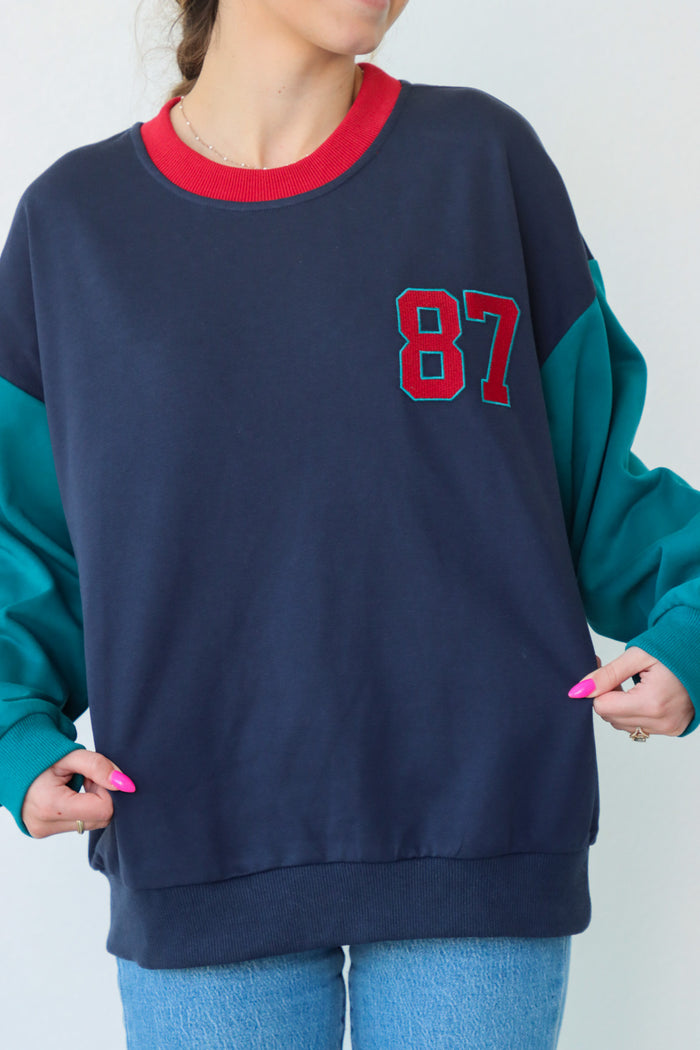 girl wearing multicolor long sleeve with "87" patchwork
